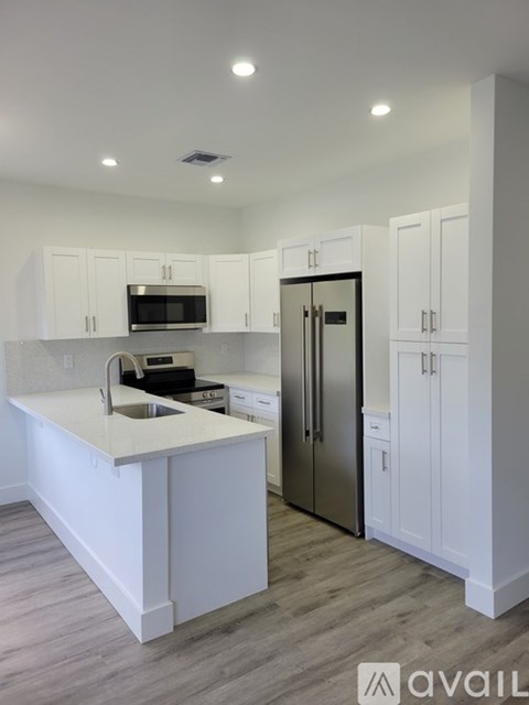 A kitchen with white cabinets and a stainless steel refrigerator.
