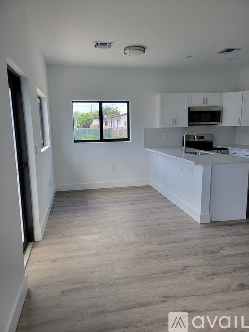 A kitchen with white cabinets and a window overlooking a street.