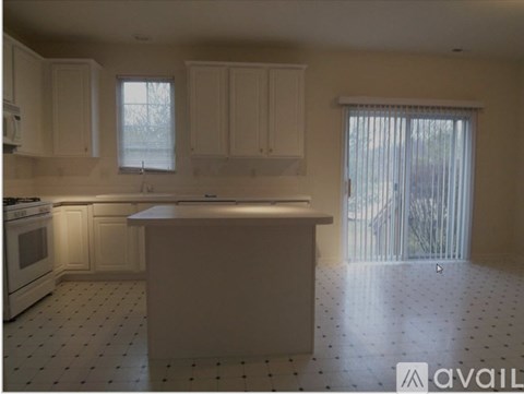 A kitchen with white cabinets and a white island.