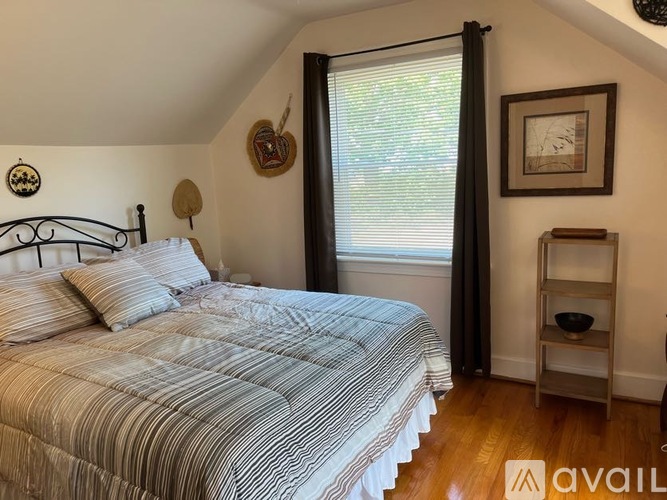 A bedroom with a bed, a window with curtains, and a shelf with a bowl on it.