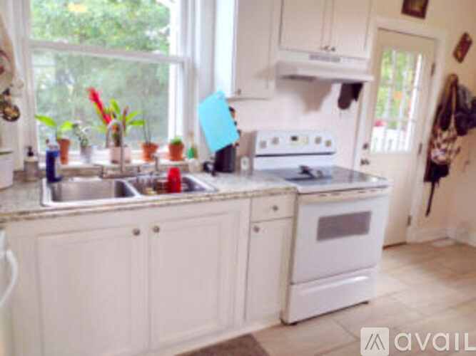 A kitchen with white cabinets and a window.