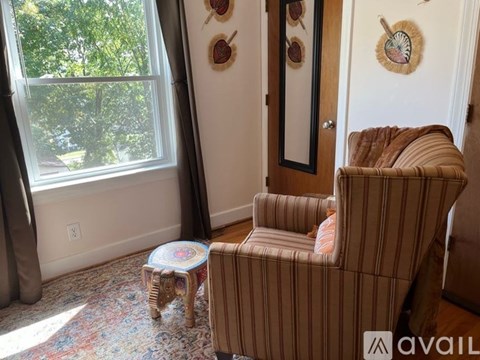 A living room with a striped chair and a small ottoman.
