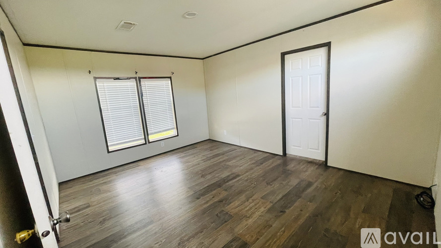 A room with wooden flooring and a window with blinds.