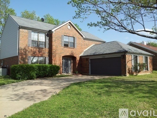 A brick house with a driveway in front.