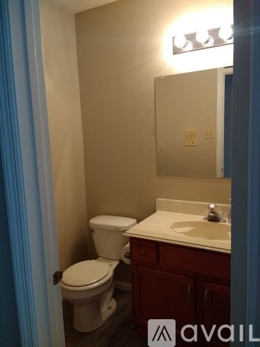 A bathroom with a toilet, sink and mirror.