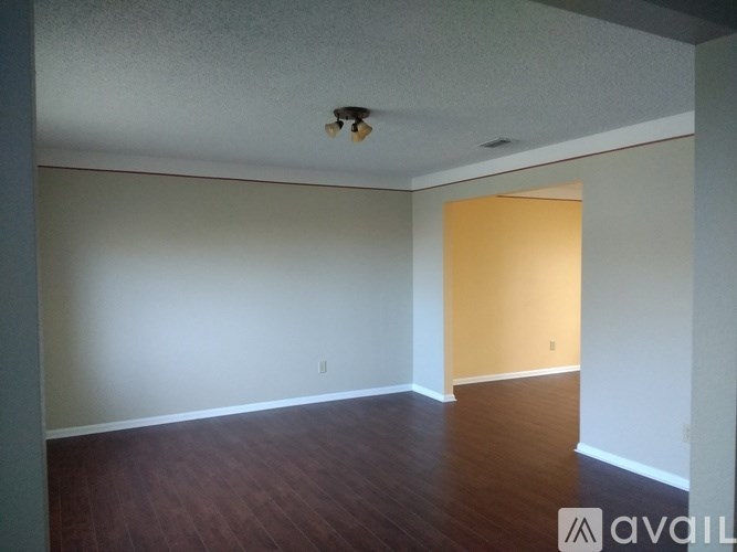A room with a wooden floor and a yellow wall.