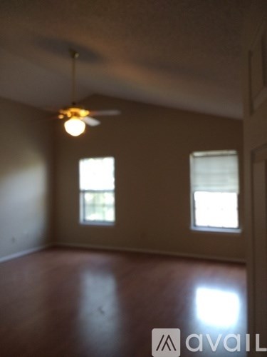 A room with a ceiling fan and two windows.