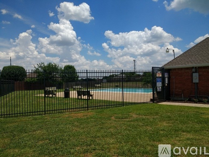 A pool surrounded by a black fence with a small building to the right.