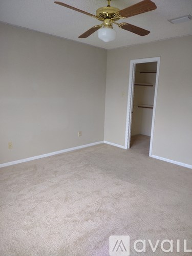 A room with a ceiling fan and carpeted floor.