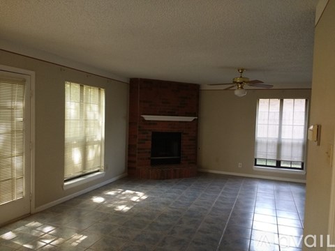 A living room with a fireplace and a ceiling fan.