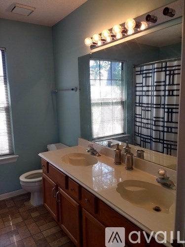 A bathroom with a toilet, sink, and mirror.