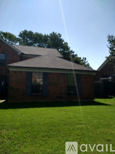 A house with a brown roof and a green lawn in front.