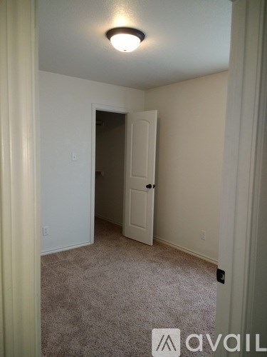 A carpeted room with a door and a light on the ceiling.