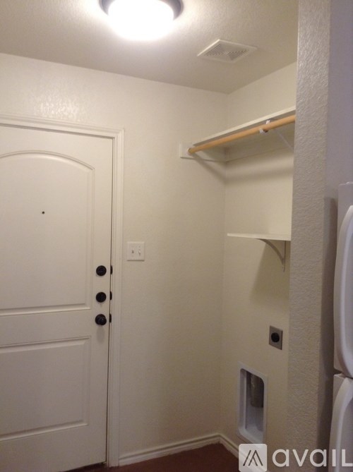 A white door with a black handle and a small square window on the wall.