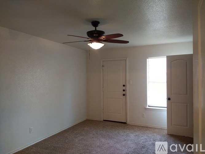 A room with a ceiling fan and a door.