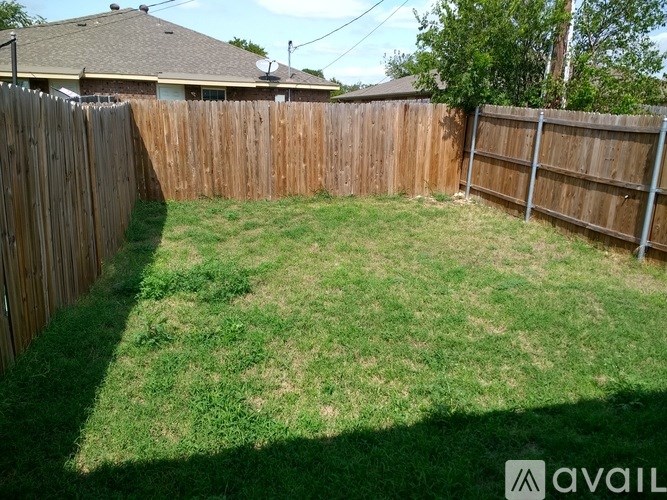 A backyard with a wooden fence and green grass.