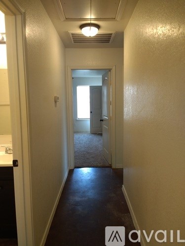 A hallway with a carpeted floor and white walls.
