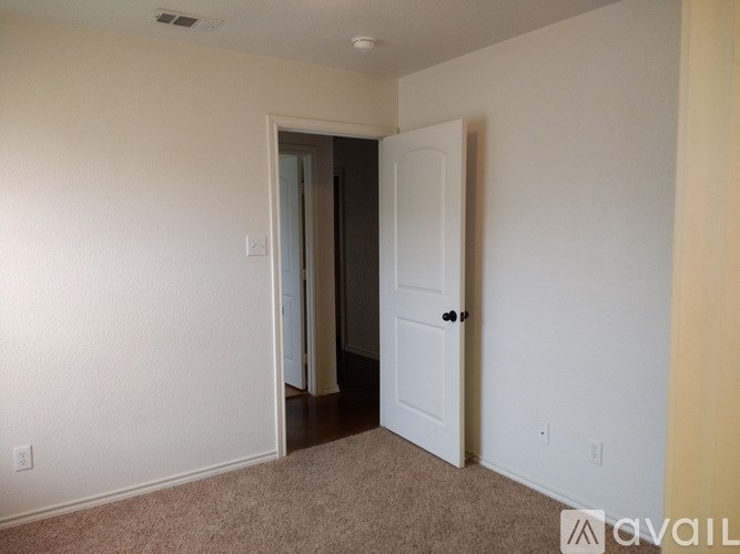 A room with a carpeted floor and two doors, one of which is open.