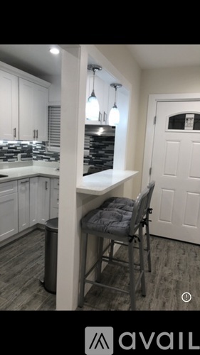 A kitchen with a white counter and a grey chair.