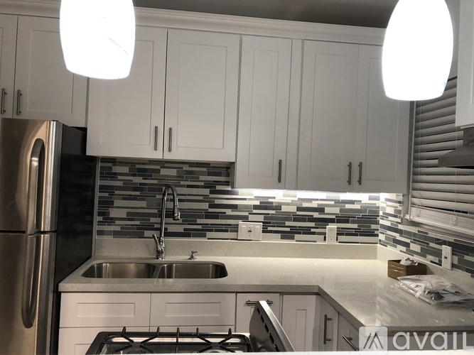 A kitchen with white cabinets and a stainless steel refrigerator.