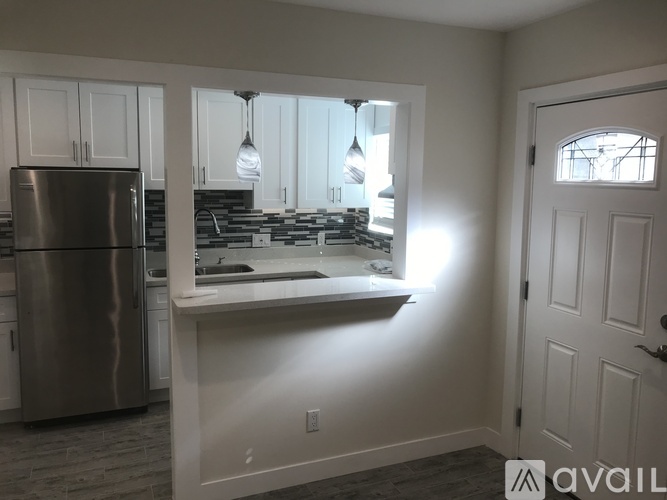 A kitchen with a stainless steel refrigerator and a window overlooking the kitchen counter.