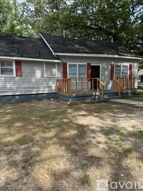 A house with a grey siding and red shutters is for sale.