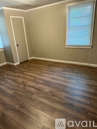 A room with wooden flooring and a window with blinds.