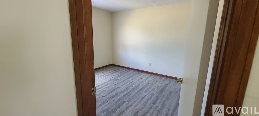 A room with a wooden floor and white walls is available for rent.