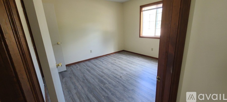 A room with a window and wooden floors is available for rent.