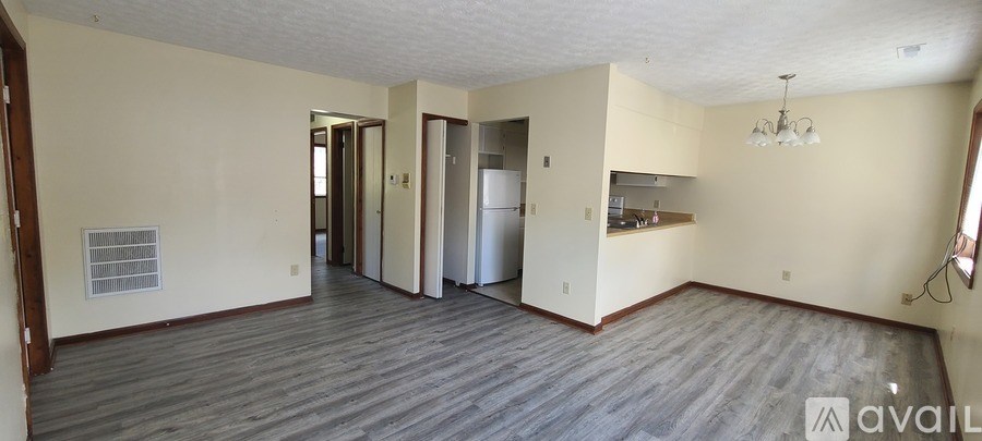 A spacious room with a kitchen area in the background.