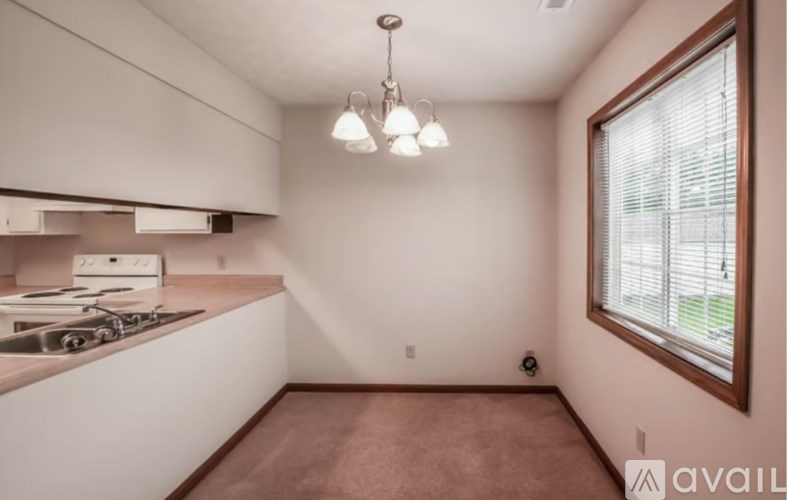 A kitchen with white cabinets and a window with blinds.