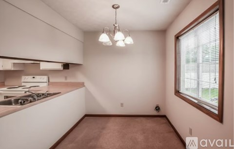 A kitchen with white cabinets and a window with blinds.