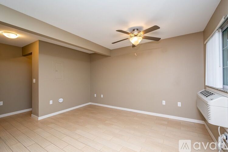 A room with a ceiling fan and a window with an air conditioner unit.