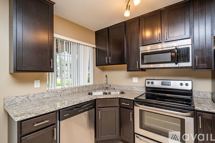A kitchen with dark brown cabinets and a granite countertop.