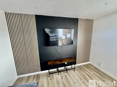 A room with wooden flooring and a white ceiling with a doorway leading to another room.