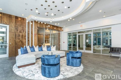 A modern living room with a white sofa, blue ottoman, and a wooden accent wall.