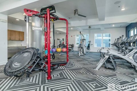A gym with a variety of equipment including a treadmill, weights, and a bench press.