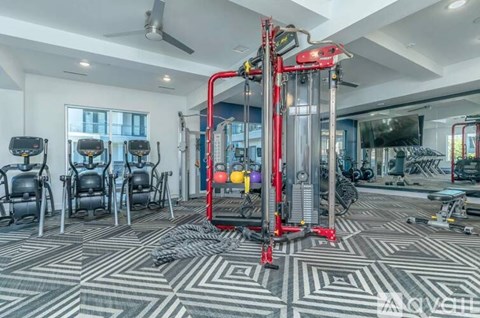 A gym with a red machine in the center and black and grey flooring.