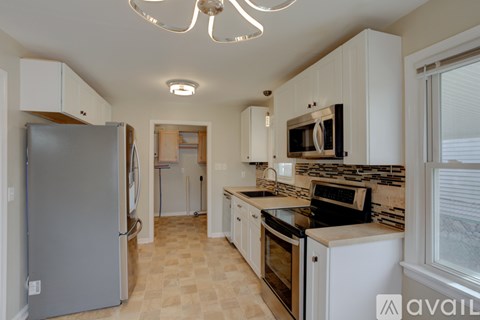 A kitchen with a refrigerator, microwave, oven, and a stove top.