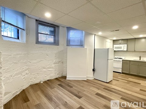 A kitchen area with a white refrigerator and wooden flooring.