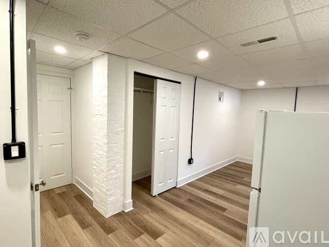 A room with a white door, a white brick wall, and a wooden floor.