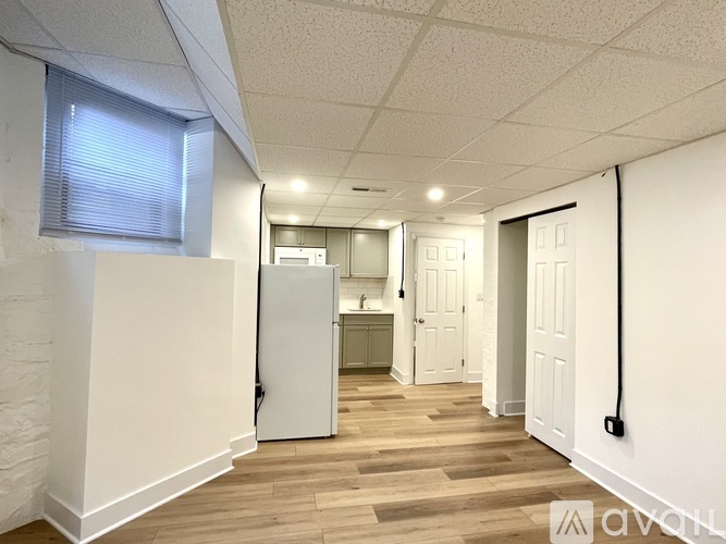 A long, narrow hallway with white walls and wooden flooring.
