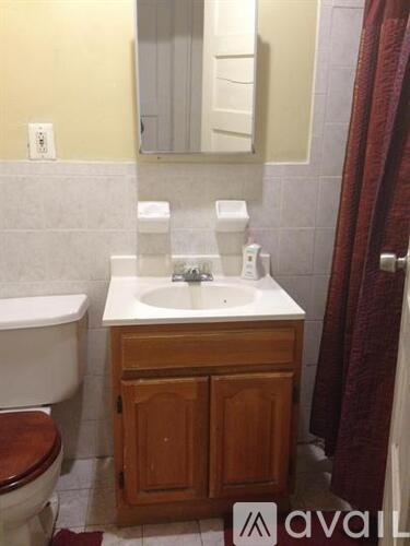 A bathroom with a toilet, sink, and mirror.
