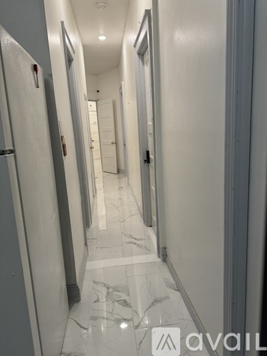 A long hallway with marble floors and white walls.