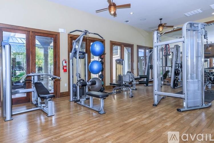 A gym with a variety of equipment including a leg press machine, a chest press machine, and a squat rack.
