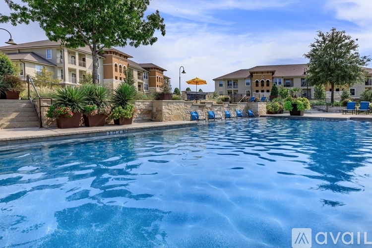 A swimming pool surrounded by lounge chairs and buildings in the background.