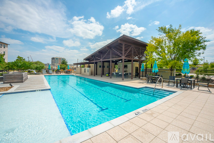 A large outdoor swimming pool with a pavilion and lounging area.