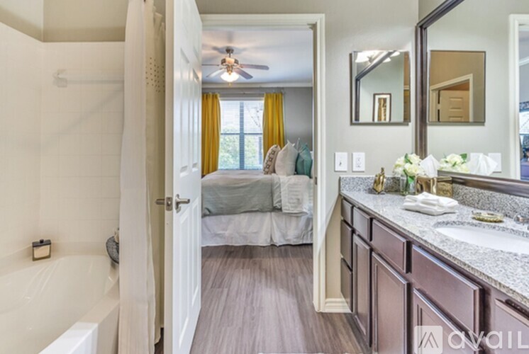 A bedroom with a bed, a vanity, and a bathtub.