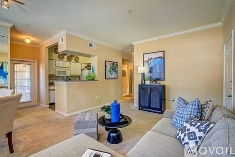 A living room with a grey couch and a blue vase on a black table.