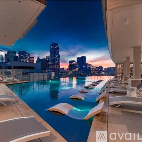 A pool with loungers and a city skyline at dusk.